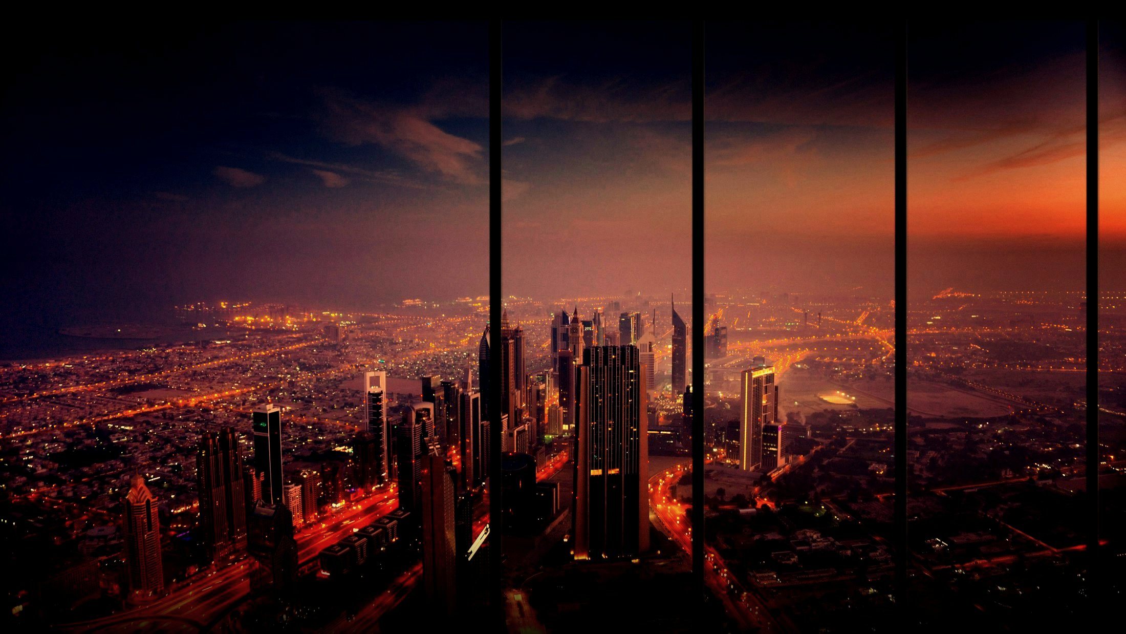 A city skyline at dusk seen through the glass walls of a high-rise meeting room